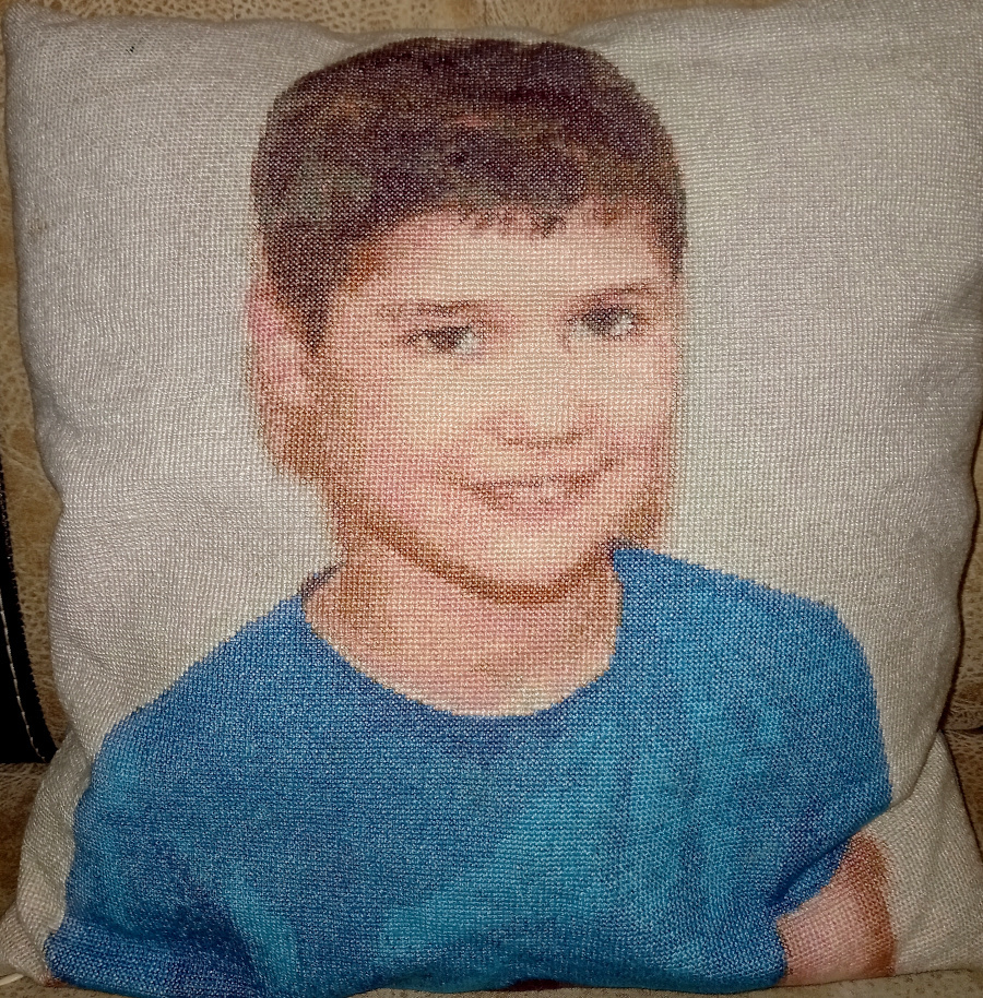 एक नीली टी-शर्ट में एक लड़के के चित्र के साथ एक तकिया क्रॉस-सिलाई डिजाइन पूरा