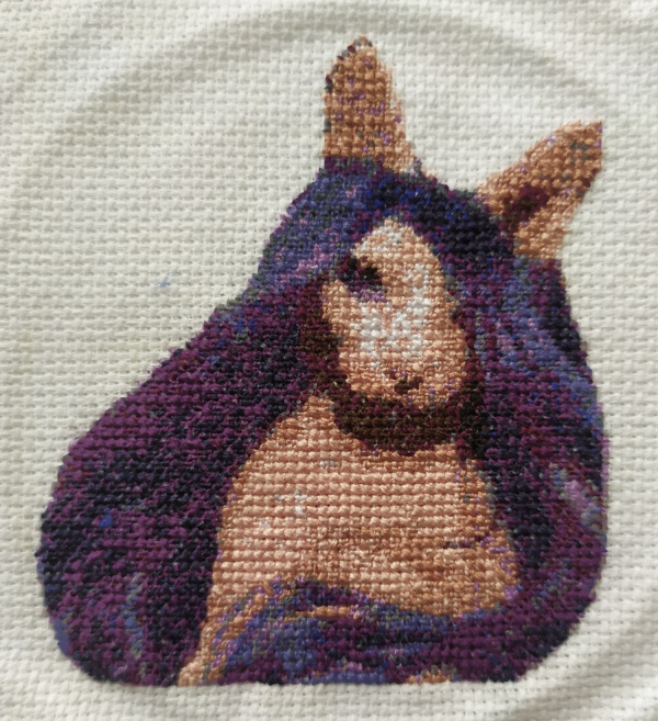 Fullfør Hårløs sfinxkatt iført en lilla parykk korsstingdesign